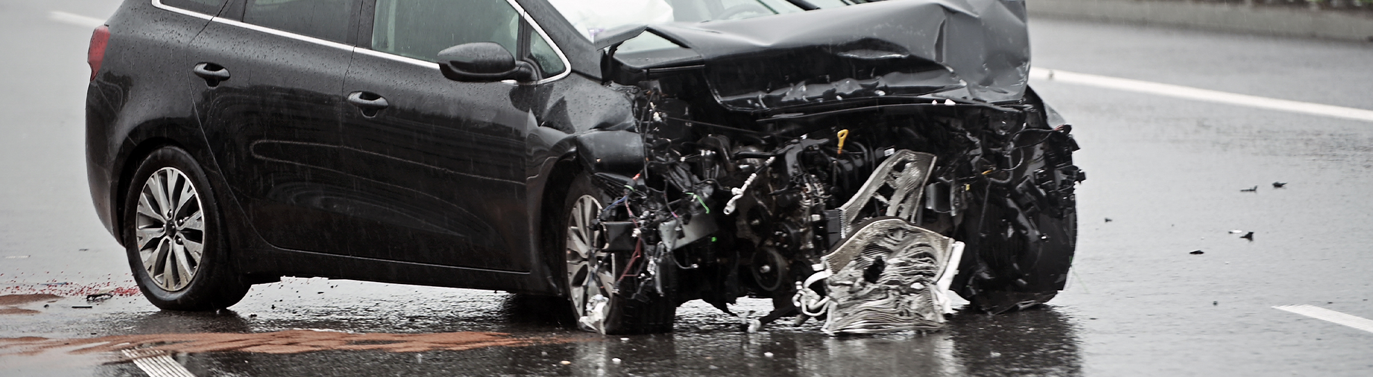 Badly Damaged Front of a Car on a Highway Right After Head On Barrier Collision in Heavy Rain