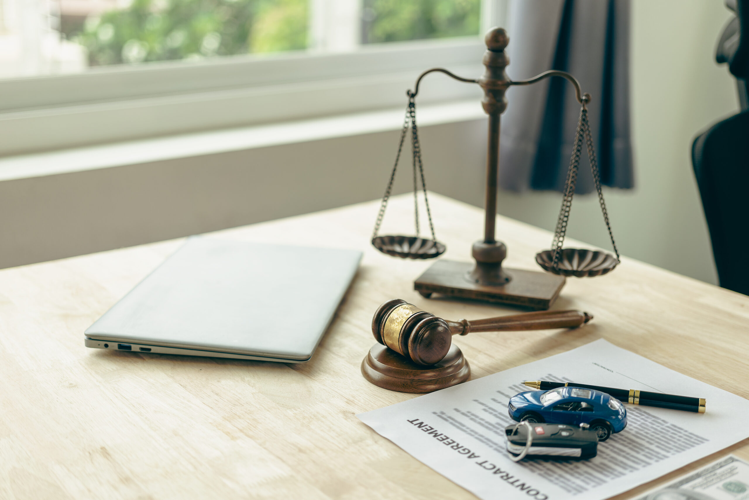 Lawyer, judge's gavel and miniature car as symbols of auction or court action against driver who got into an accident and received car insurance money on the table. Close-up view.